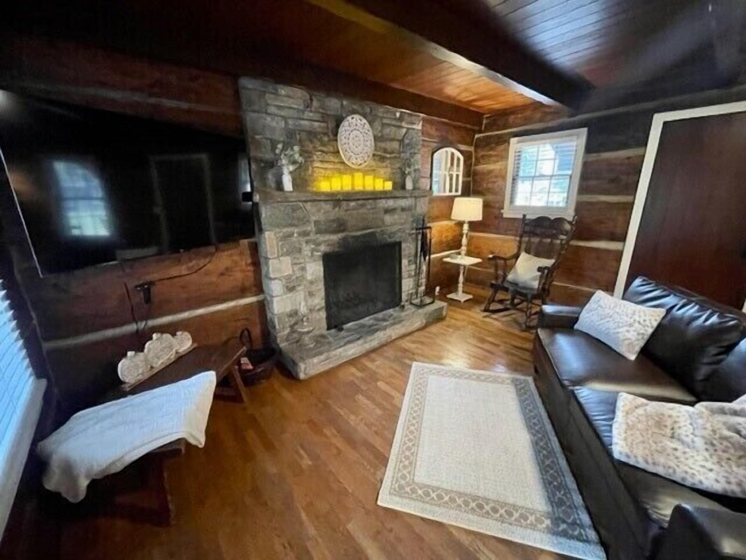 A cozy living room with a stone fireplace, a leather sofa, and a television.