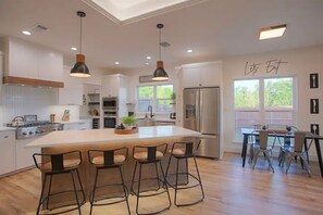 A modern kitchen with a large island, bar stools, and a dining area with a table and chairs.