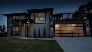 A modern two-story house with a stone facade, large windows, and a garage. - The Rooftop (Denison)