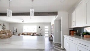 Une cuisine moderne avec des meubles blancs, un grand îlot central et un sol décoré d’un motif en chevrons.