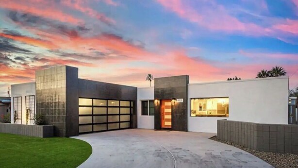 Un bâtiment moderne doté d’un garage, d’une pelouse bien entretenue et surplombant un ciel au coucher du soleil.