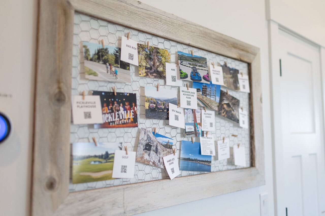 A bulletin board with various travel-related photos and QR codes pinned to it.