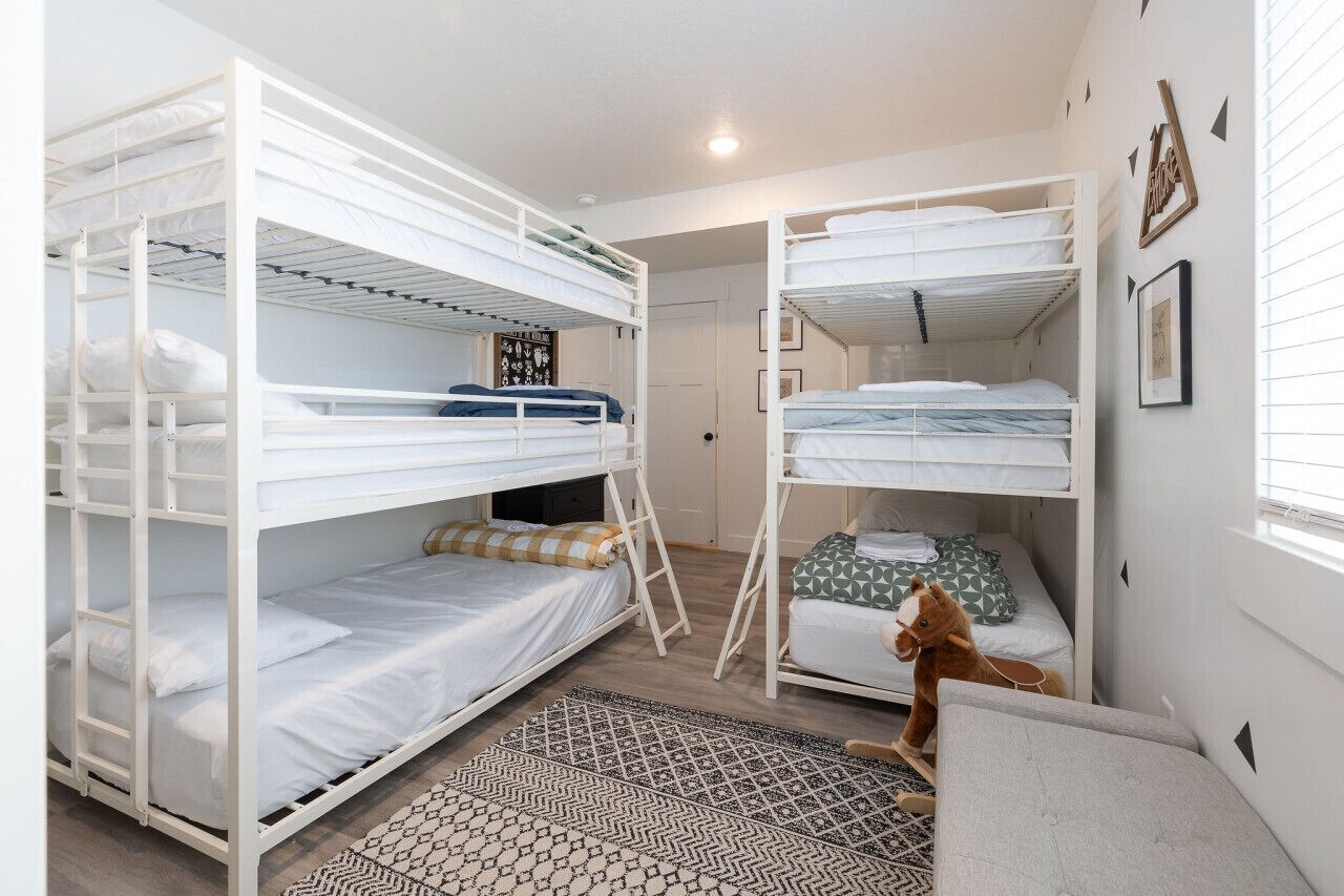 A bunk bed room with a ladder, a patterned rug, and a horse toy.