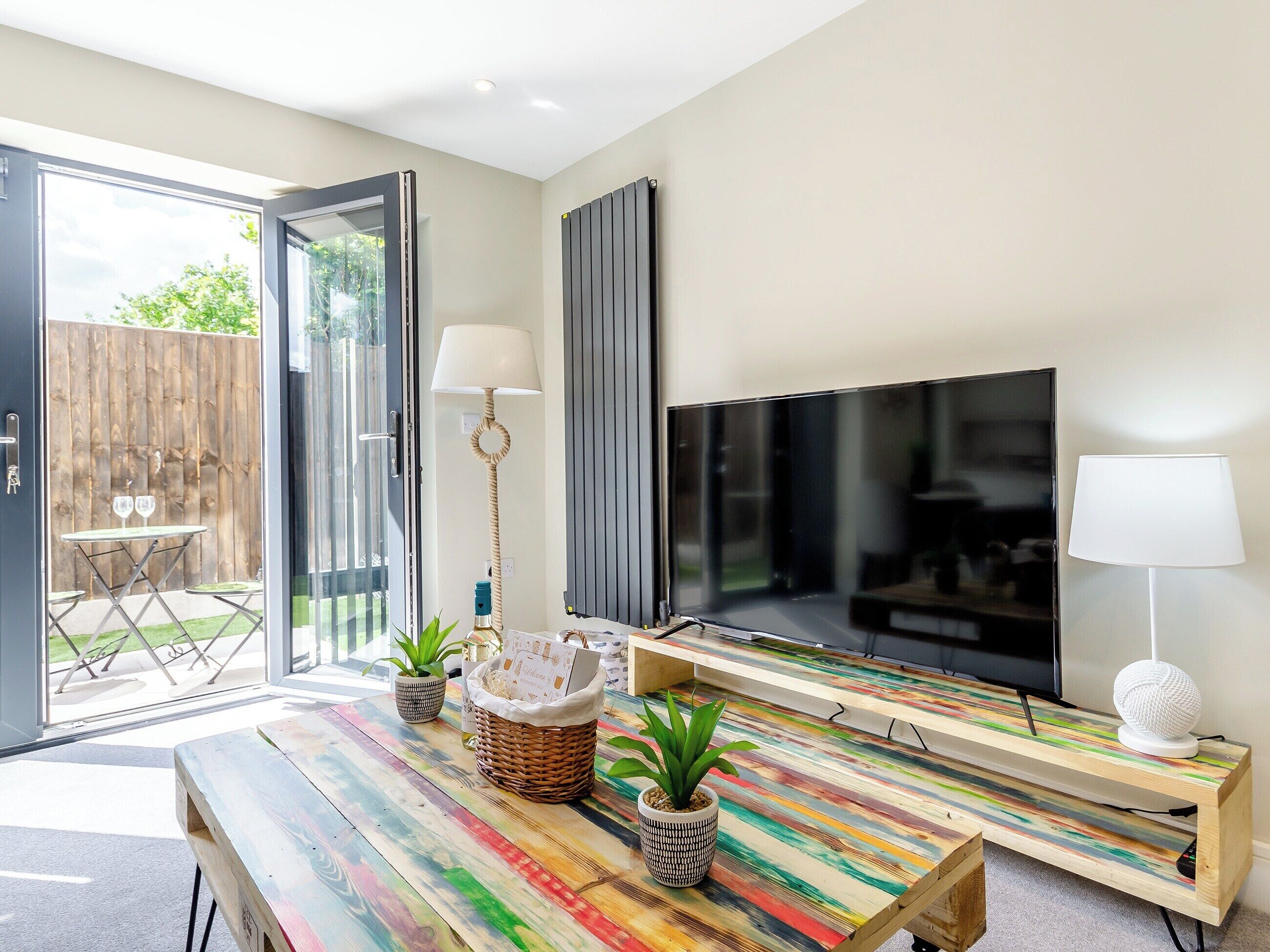 A modern living room with a large TV, a wooden coffee table, and a dining table.