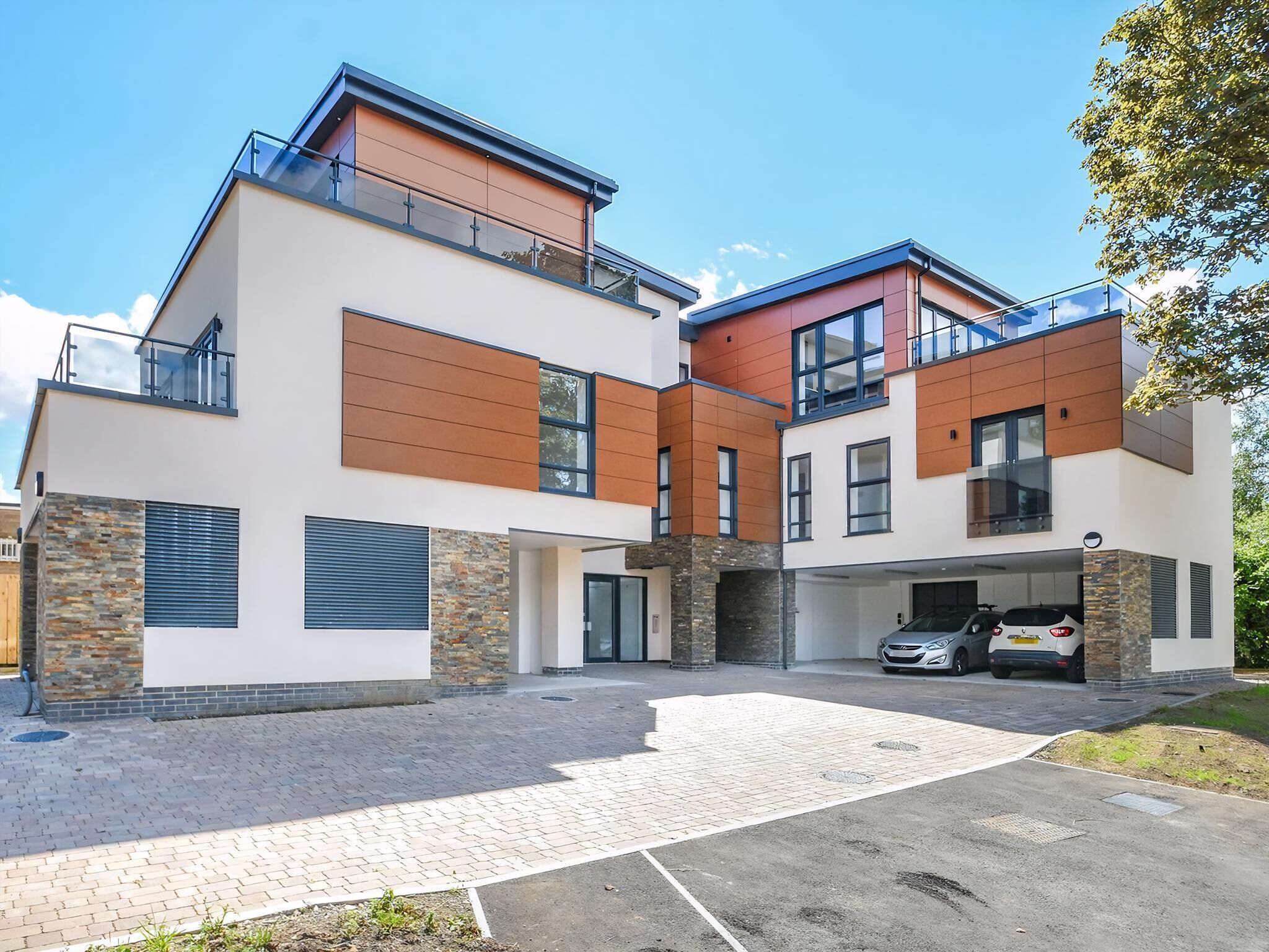 A modern two-story house with a garage, stone accents, and a paved driveway.