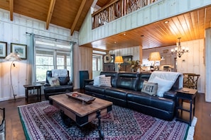 A cozy living room with a black leather sofa, a wooden coffee table, and a patterned rug. - Sweet Sapphire Getaway! Enjoy the mountains!! (Sapphire)