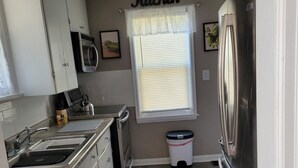 A kitchen with white cabinets, a stainless steel refrigerator, a microwave, and a sink. - Clean, quiet and perfectly located in the city.  Near downtown. (Columbus)