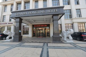 La entrada al Hotel Guanda Hongting, con un patrón de piso a cuadros y dos estatuas blancas de elefantes a cada lado.