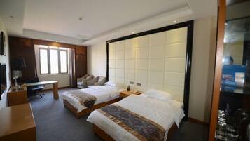 A hotel room with two beds, a desk, a chair, and a large window.