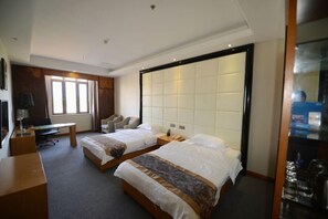 Una habitación de hotel con dos camas, un escritorio, una silla y un ventanal grande.