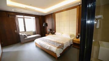 Habitación de hotel con una cama grande, un sofá, una mesita de noche, una lámpara y vistas al exterior.