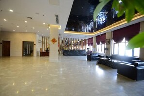 A spacious lobby with a reception desk, seating area, and a high ceiling with recessed lighting. - Guanda Hongting Hotel (Fuqing)