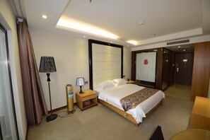 Una habitación de hotel con cama, mesita de noche, lámpara y un espejo grande.