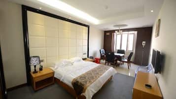 Habitación de hotel con cama, mesita de noche, lámpara, escritorio, silla y televisor.