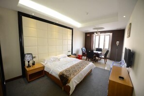 Habitación de hotel con cama, mesita de noche, lámpara, escritorio, silla y televisor.