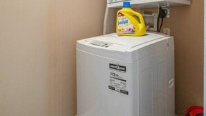Ein kleiner Hauswirtschaftsraum mit einer Waschmaschine mit Frontlader und einem darüber platzierten Trockner.