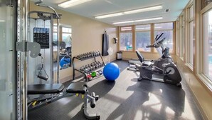 Ein Fitnessraum mit Trainingsgeräten, einem blauen Übungsball und einem Fenster mit Blick.