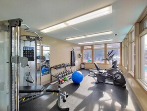 A gym with exercise equipment, a blue exercise ball, and a window with a view. - Hart of it All | Top Floor | Pool | Hot Tub | Gym (Invermere)