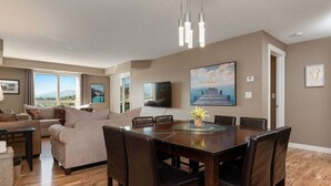 A modern living room with a dining area, a large window, and a flat-screen TV.