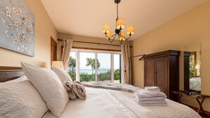Un dormitorio con una cama grande, una araña, un armario y vistas al exterior.