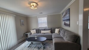 Un salon avec un canapé d’angle, une table basse ronde et un tapis à motifs.