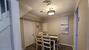 Un espace repas comprenant une table et des chaises, un luminaire au plafond et une porte.