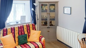 A living room with a patterned sofa, a cabinet with glass doors, and a radiator. - 2 bedroom accommodation in Llanrwst (Llanrwst)