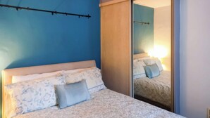 A bedroom with a bed, a wardrobe, and a mirror. - 2 bedroom accommodation in Llanrwst (Llanrwst)