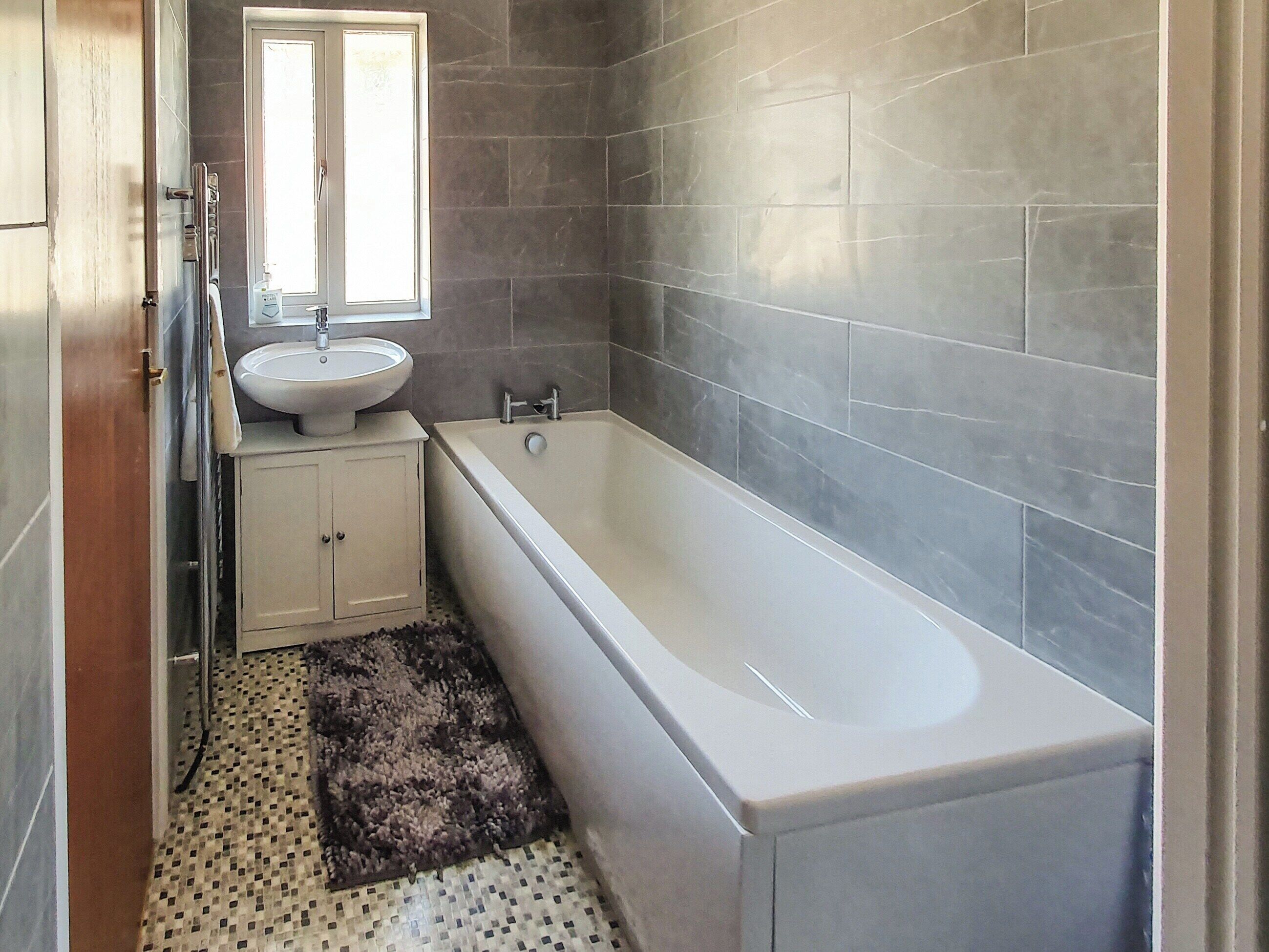 A bathroom with a bathtub, a sink, and a window.