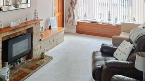 A living room with a fireplace, a television, and a sofa with decorative pillows.