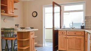 A kitchen with wooden cabinets, a clock, and a window.