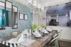Enjoy meals in this stylish dining area with a long table, chandelier, and large mirror.
