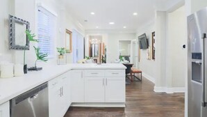 A modern kitchen with white cabinetry, a built-in dishwasher, and a central island. - ⭐️Old 4th Ward⭐️ Designer Duplex Home - 2 Minutes from Downtown! (Atlanta)