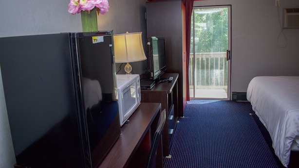 A hotel room with a bed, a desk with a computer, a TV, a microwave, and a vase with flowers. - Travel Inn (North Kingstown)