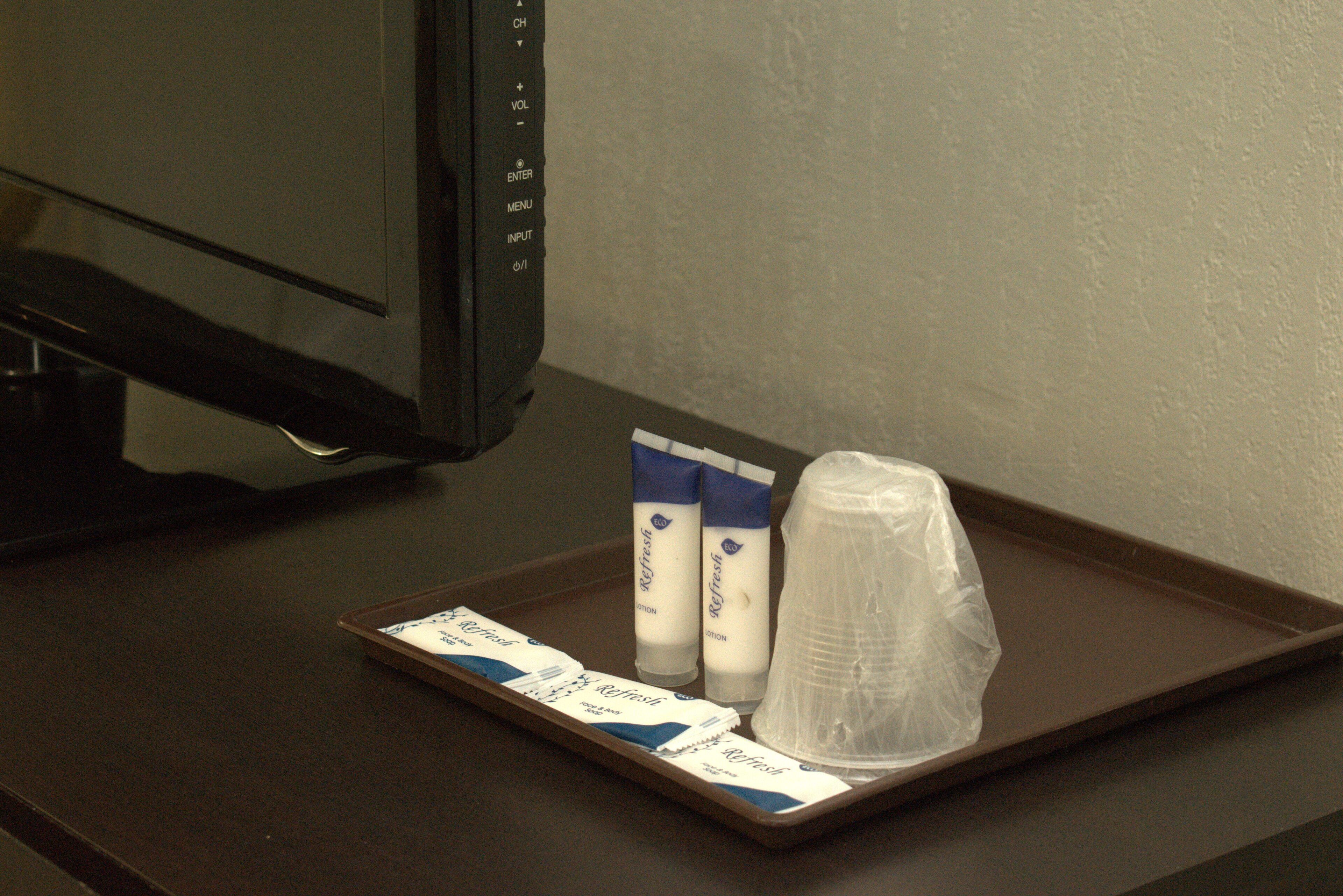 A tray with a plastic cup, two tubes of lotion, and a tray liner on a dark surface.