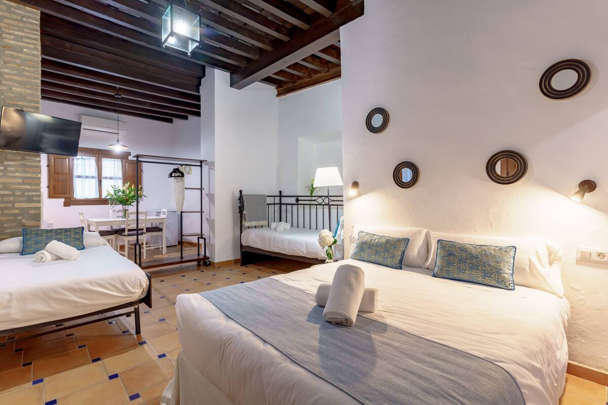 A hotel room with two beds, a dining area, and a bathroom.