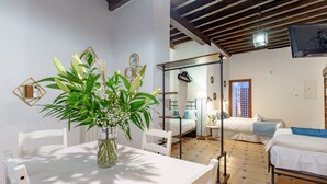 A room with a dining table, chairs, a bed, and a small window. - SUITES CASA DE LAS COLUMNAS (Granada)