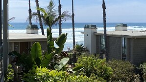 A view of a beachfront property with palm trees and ocean waves. - Pearl on the Strand - Ocean and Village Views at Oceanside Beach! (Oceanside)