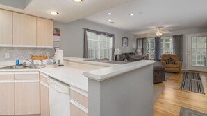 A modern kitchen with a central island, a dining area with a sofa, and a living room with a chair. - Lakeside Condo on Lake Taneycomo (Branson)