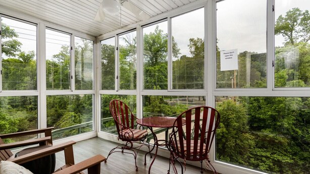 A conservatory with a wooden floor, a table, and two chairs. - Lakeside Condo on Lake Taneycomo (Branson)