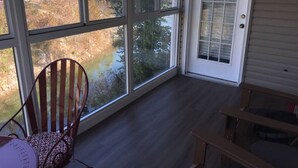 A room with large windows, a chair, and a table. - Lakeside Condo on Lake Taneycomo (Branson)