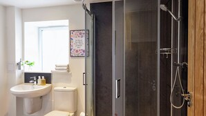 A modern bathroom with a glass-enclosed shower, a sink, a toilet, and a window. - Hope Cottage - UK40055 (Aberfeldy, near Pitlochry)