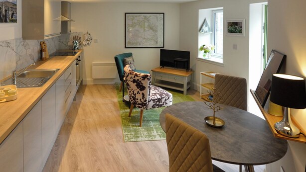 A modern kitchen with a dining area, a TV, and a window with a view. - Hope Cottage - UK40055 (Aberfeldy, near Pitlochry)