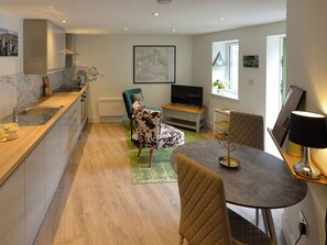 A modern kitchen with a dining area, a TV, and a window with a view.