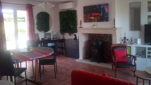 A living room with a fireplace, a dining table, and a TV. - Beautiful view over the heights of Sarlat in a quiet, not overlooked location with air-conditioned swimming pool. (Sarlat-la-Canéda)