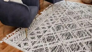 Una sala de estar moderna con dos sillones azul oscuro, un tapete blanco estampado y una mesita redonda.