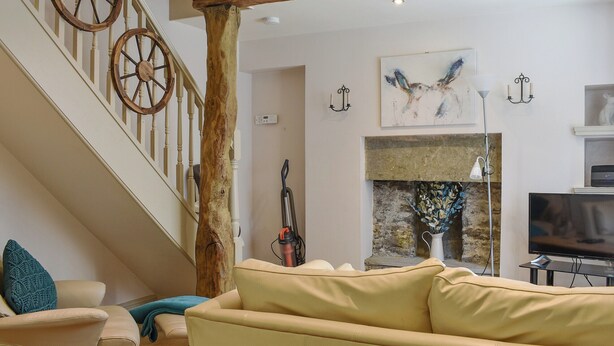 A living room with a staircase, a sofa, a painting, a fireplace, and a television. - 2 bedroom accommodation in Hawes (Hawes)