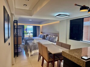 A modern hotel room with a large bed, a dining area, and a balcony with a view. - MARINAS PRAIA FLAT (João Pessoa)