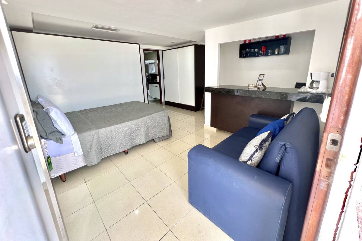 Ein kompaktes Hotelzimmer mit Bett, einer Sitzecke, einer Küchenzeile und einem kleinen Badezimmer.