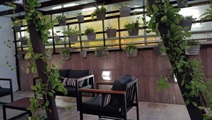 A modern indoor seating area with black chairs and a wooden wall. - MARINAS PRAIA FLAT (João Pessoa)